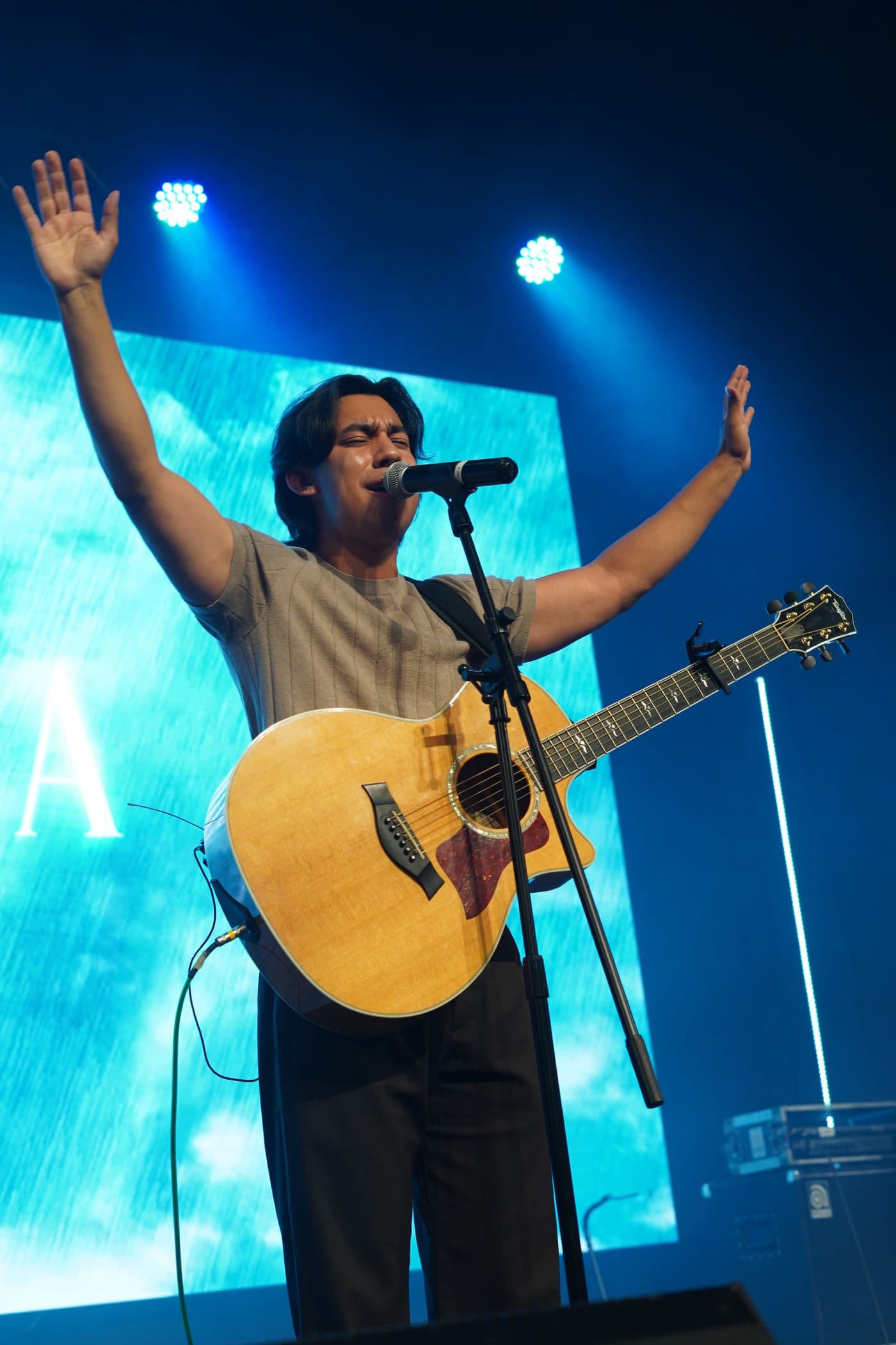 Juan Poumian cantando con los brazos abiertos y su guitarra acústica