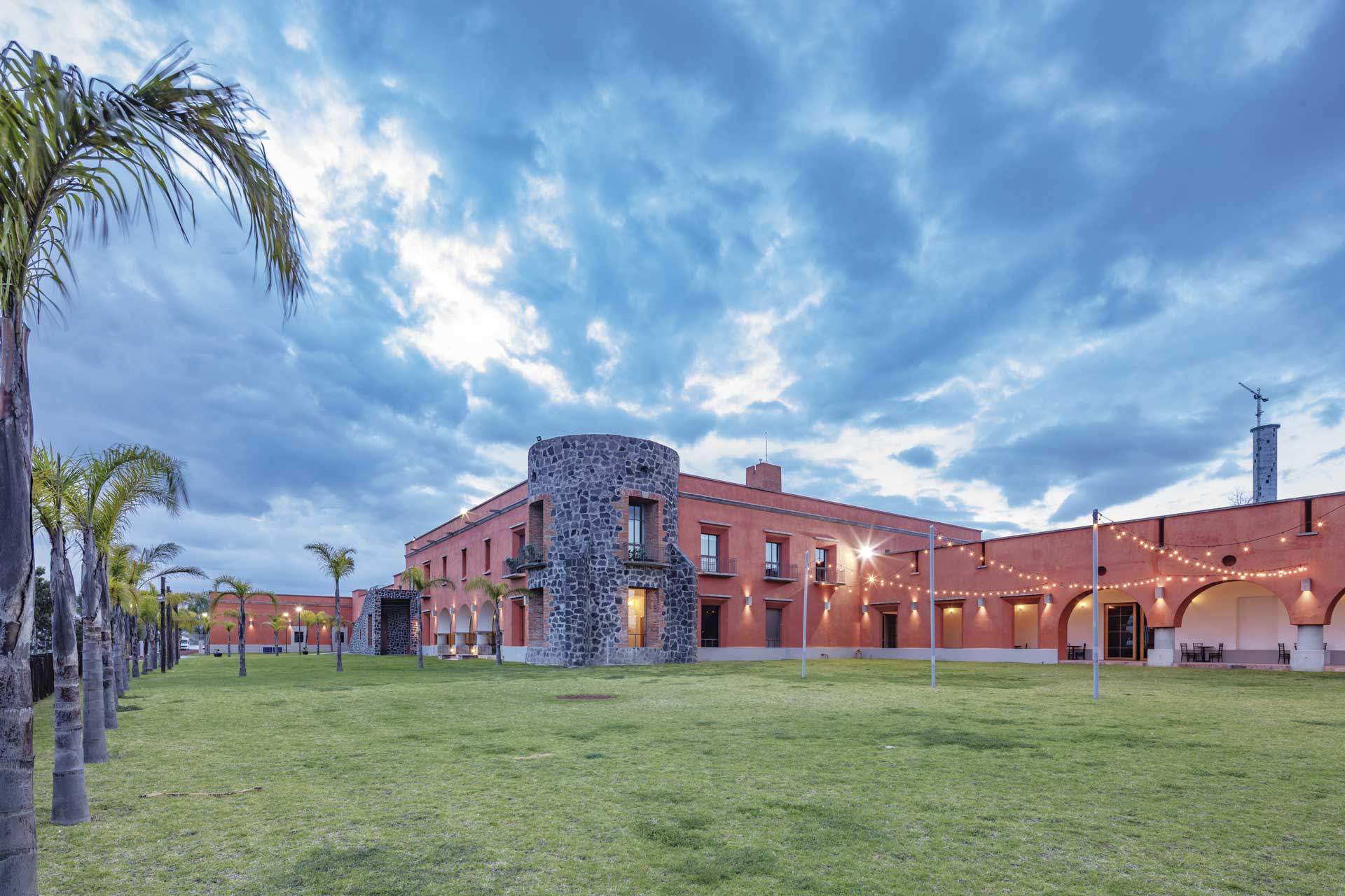 Fachada de Hacienda Paz al atardecer, con su torre de piedra y arcos iluminados